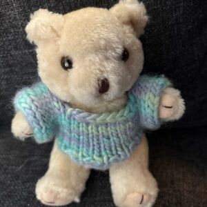 Cute 5 inch jointed bear wearing a blue and purple variegated knitted sweater